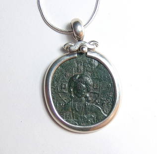 A choice Byzantine bronze coin set into a lovely silver: A choice Byzantine bronze coin set into a lovely silver bezel with chain. The coin is struck during the reign of Romanus III, AD 1028 - 1034, at Constantinople. The coin is set in a lovely .925