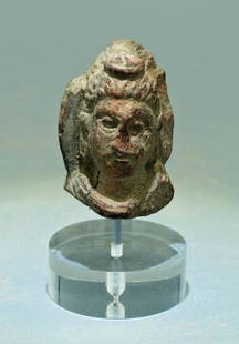 A nicely carved Gandharan stone head: A nicely carved Gandharan stone head, Indus Valley, c. 3rd - 4th Century AD. This choice fragment is carved from a red hardstone and depicts Buddha with an intricately detailed coif gathered in a