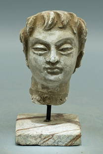 A beautiful Gandharan stucco head: A well-carved Gandharan stucco head, Indus Valley, c. 4th - 5th Century AD. A detailed sculpture which is carved from stucco depicting a young man with detailed coif. H: 2 3/4 in (6.9 cm). Traces of