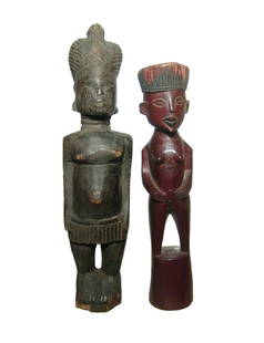 A pair of African wooden female figures: A pair of African wooden female figures. The first possessing definite age with elaborate hair, rings on neck and wearing a short skirt. H: 13 3/8 in (33.8 cm). The second is in the form of a woman