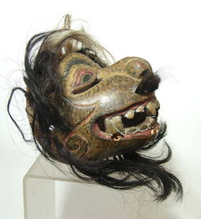 An antique polychrome wood mask from Bali: An antique polychrome wood mask from Bali, early 20th Century, in the form of a toothed feline, with added hair. The surfaces are well-preserved with black and red detail over yellow and definitely