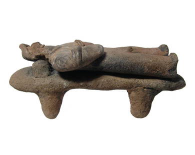 A ceramic Colima man lying on a bed: A ceramic Colima man lying on a bed, West Mexico, 100 BC - AD 250, he is depicted nude wearing a pointed headdress, earrings, armlets and a necklace, his face well-detailed. He lays atop a