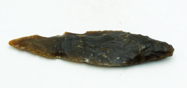 A large Maya flint spear point: A large Maya spear point, Guatemala, c. AD 400 - 700, fashioned from translucent, root beer colored flint. L: 7 1/2 in (19 cm). The edges are still sharp, and the weapon shows signs of wear from use.
