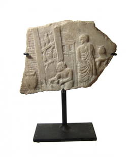 A wonderful Roman marble relief depicting a potter’s sh: A wonderful Roman marble relief depicting a potter’s shop, c. 2nd Century AD, the potter is seen sitting at his wheel or low table attaching a handle to an amphora. Around him finished vessels and