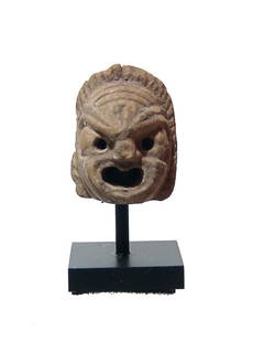A rare and cute Roman ceramic actor's mask amulet: A cute and particularly rare Roman ceramic amulet in the form of an actor's mask, c. 1st - 3rd Century AD, with nicely detailed features and a small suspension loop at back. H: 16 mm. Light deposits