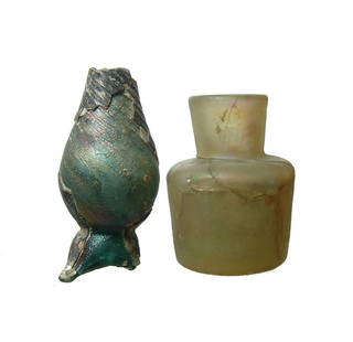 A pair of glass vessels, Roman and Post-Medieval: A pair of glass vessels. The first is a fragmentary Roman bottle, c. 2nd - 4th Century AD, in blue-green glass, the ovoid body on applied tripod foot, H: 2 3/4 in (6.9 cm). The second vessel is a