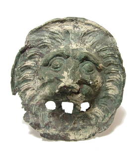 An attractive bronze facing lion head applique: An attractive bronze facing lion head applique, 2nd - 3rd Century AD, slightly oval in shape and formed from sheet bronze pounded over a wood or metal form. The applique is nicely embossed with large