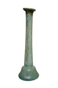 A tall Roman pale blue glass bottle: A tall Roman pale blue glass bottle, 2nd - 3rd Century AD, the body bell-shaped with indented bottom, the neck is long and tubular with wide, flattened rim. H: 6 7/8 in (17.5 cm). Attractive