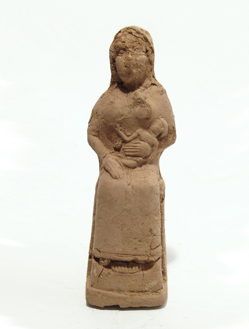 An Old Babylonian terracotta seated woman: An Old Babylonian terracotta seated woman, c. 1900 - 1750 BC, the woman sits on her throne suckling an infant who she cradles with her left arm, in the manner of the goddess Isis who suckles the young