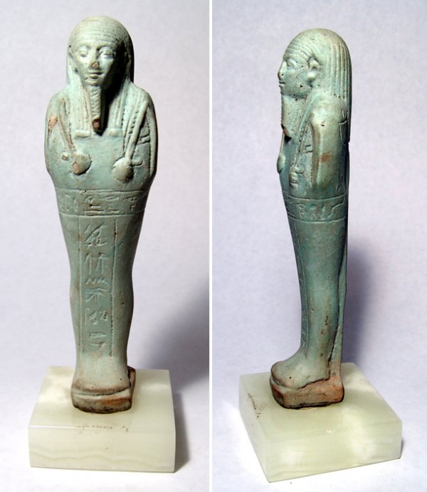 Ushabti with fine striated wig, hoe and seed bag: Detailed pale blue ushabti with handsome features and good detail. Wearing striated wig and holding pick, hoe and seed bag. 'T' style inscription and plinth down back. Late Period, 664 - 343 BC. H: 6 