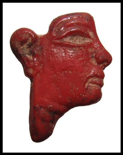 Egyptian glass inlay of a male face: A beautiful glass inlay of a male face, Late Period, c.664 - 343 BC, of bright red color and excellent workmanship. The eye is open for additional inlaid color and the piece what have been inset into 