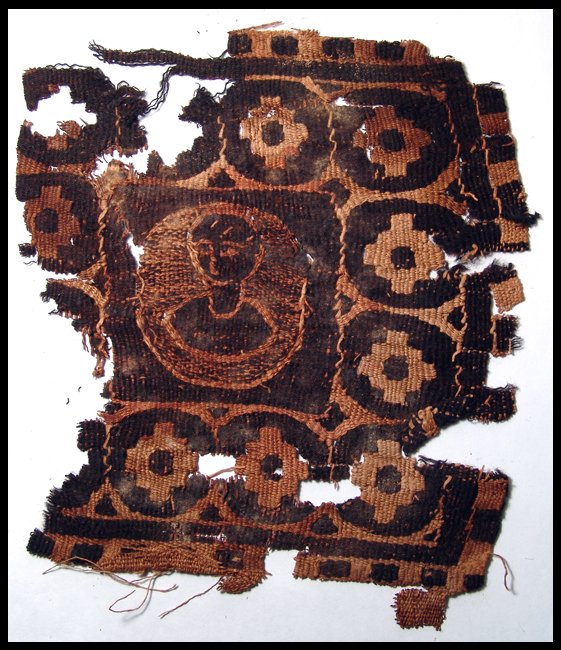 Large textile panel depicting the bust of a youth: A large textile panel depicting the bust of a youth, Roman Egypt, 4th - 5th century AD. The bust is stylized with short cropped hair and sits within a decorated border. 6 ½" (16.6 cm) x 7" (18 cm). B