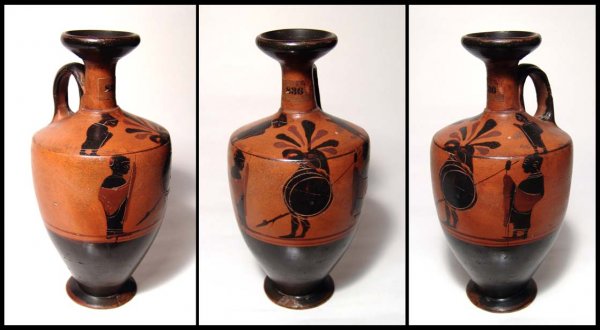 Attic black-figure lekythos, Ex Evrard, France: An Attic black-figure lekythos, c.530 - 510 BC, featuring a helmeted warrior holding a shield and spear facing another warrior, behind stands his arms bearer. On the shoulder, a palmette between two h