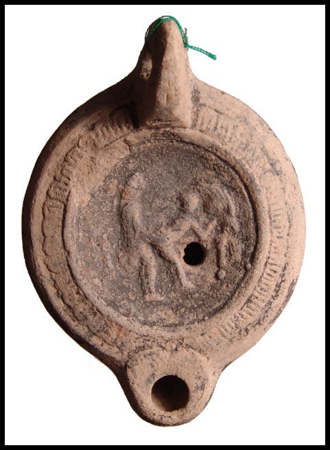 Roman terracotta lamp with erotic scene: A Roman terracotta lamp with erotic scene, c.2nd Century AD, mouldmade with herringbone pattern around central discus. Scene involves a woman leaning over a couch, head facing, her partner penetrating