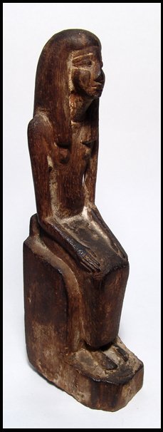 New Kingdom. Wooden seated woman figure: Ancient Egypt. A tall, wooden seated figure of a woman, New Kingdom, 1570 - 1075 BC. She sits wearing long wig and long dress, hands placed before her on her lap. She sits on a large seated with base 