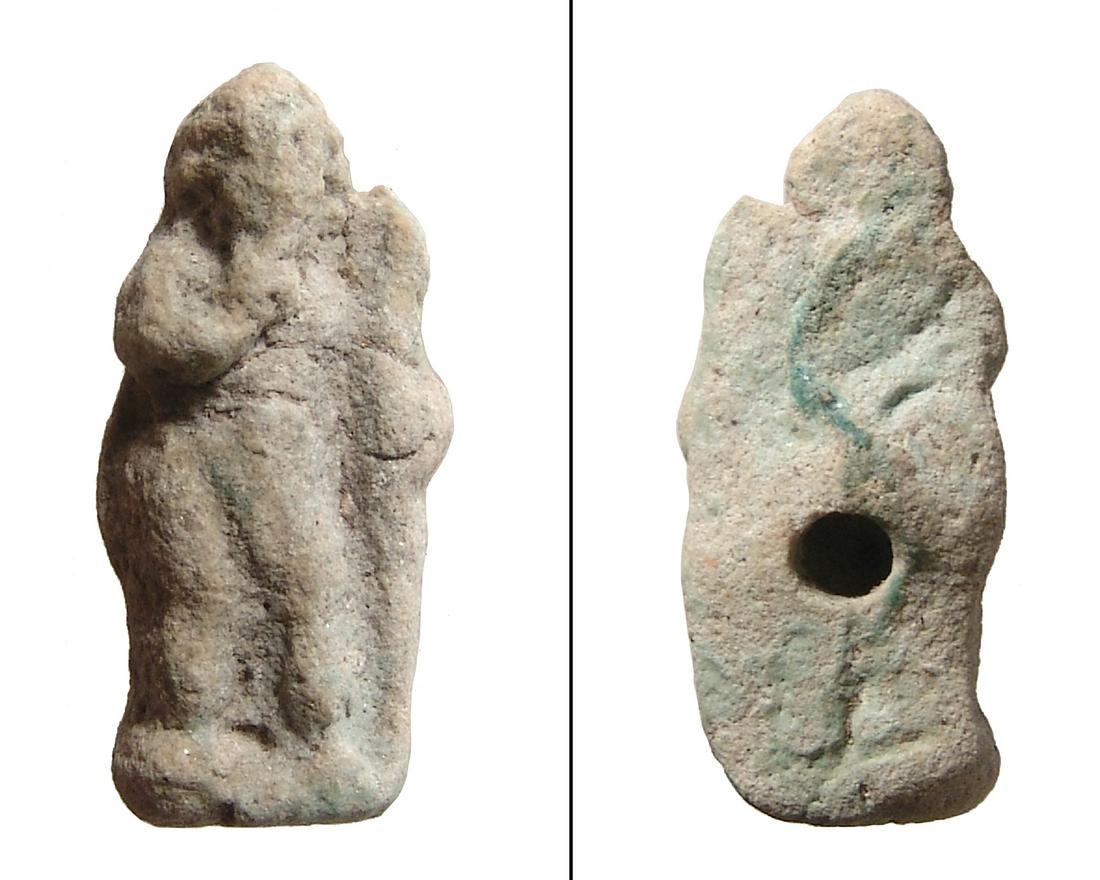 Egyptian faience amulet of Harpokrates, Roman Period: An Egyptian faience amulet of Harpokrates, Roman Period, c. 1st Century BC - 1st Century AD, nude, standing next to a large torch or cornucopia, around which he wraps his left arm, right finger to mou