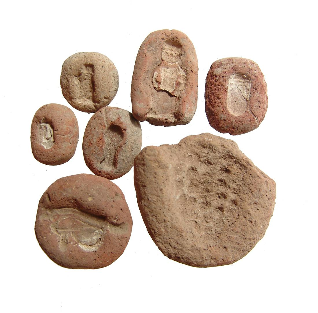 Lot of 7 Egyptian terracotta molds, New Kingdom: A lot of 7 Egyptian terracotta molds, New Kingdom, c. 1570 - 1075 BC, and include a large mold for a bunch of grapes, another for an Eye of Horus amulet, one for an amulet of Pataikos, an example with