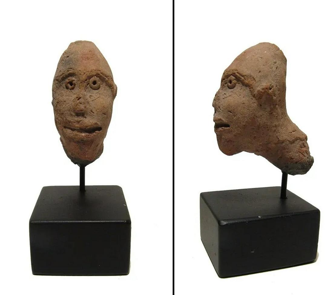 An Egyptian molded terracotta head of a man: An Egyptian molded terracotta head of a man, c. 1st Century BC/AD, with oval face and wearing a domed headdress, his features nicely detailed. An interesting piece which could be from the corner of a 