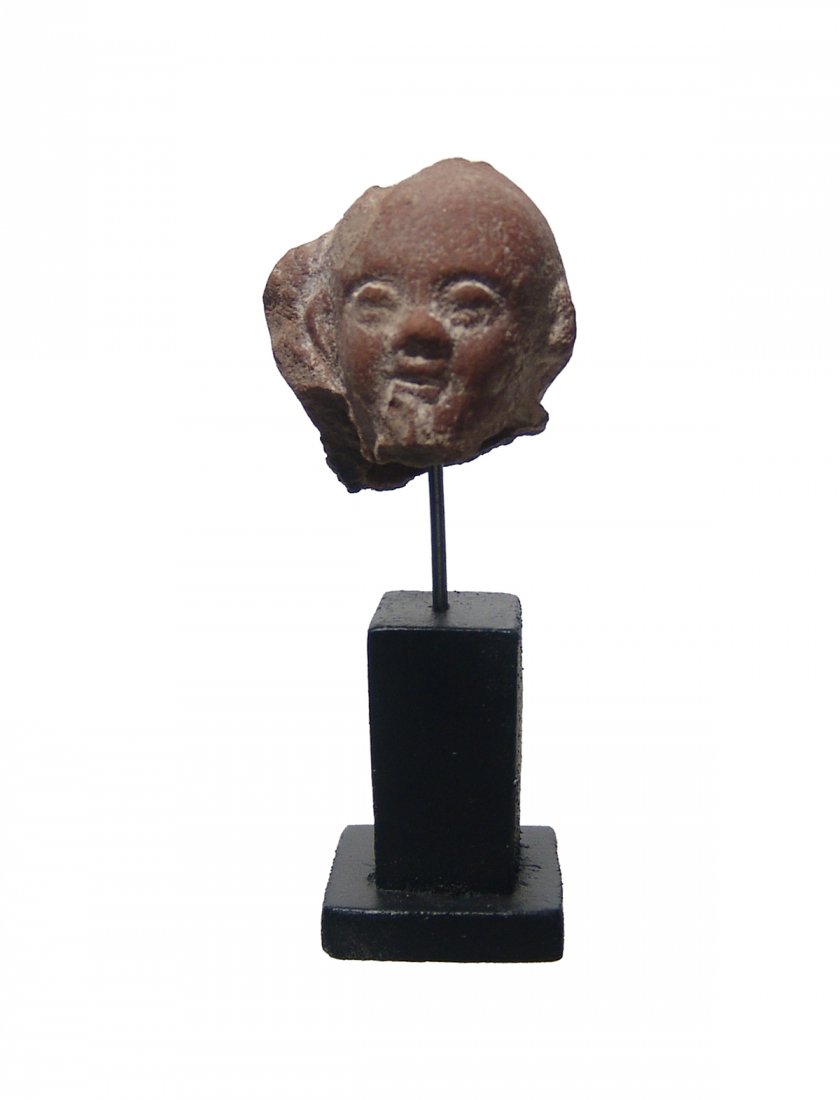 Romano-Egyptian terracotta head of Harpokrates: A Romano-Egyptian terracotta head of Harpokrates, 1st - 2nd Century AD, with side lock and remnants of right finger at lips, his features quite attractive. H: 1 3/4 in (4.4 cm) with wood stand. Ex Nor