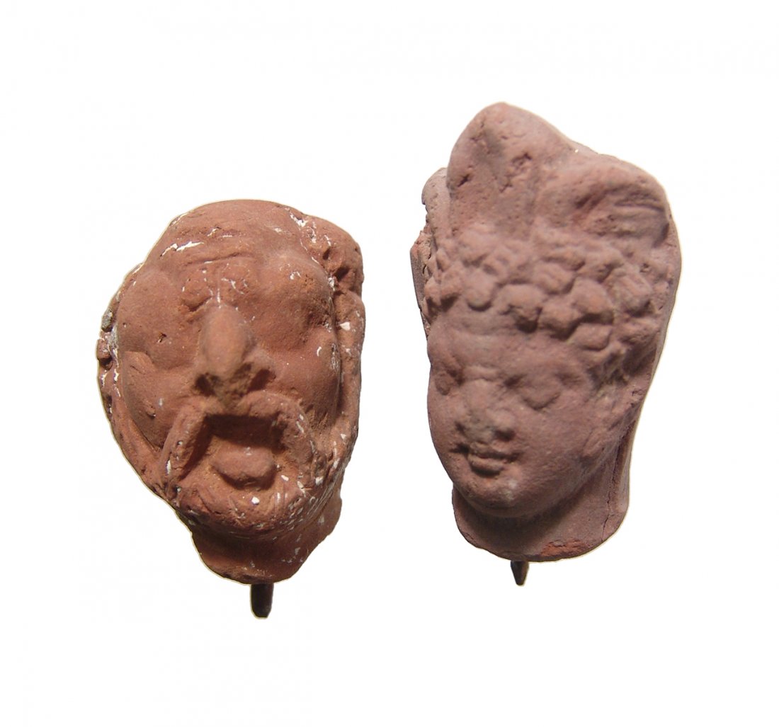 A pair of Romano-Egyptian terracotta heads: A pair of Romano-Egyptian terracotta heads, c. 1st - 2nd Century AD, one depicting a bearded man, and the other a woman wearing a feathered wreath. Largest 1 7/8 in (4.7 cm). Ex Harvith collection, MI