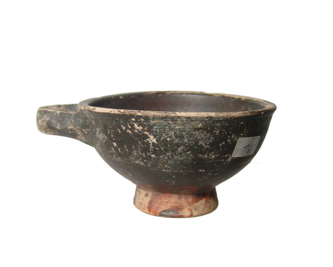 A cute Greek black ware cup: A cute Greek black ware cup, 4th Century BC, the hemispherical bowl with flattened rim and raised foot with horizontal oriented loop handle. 2 x 4 5/8 in (5 x 11.7 cm). Light deposits. Ex German priva