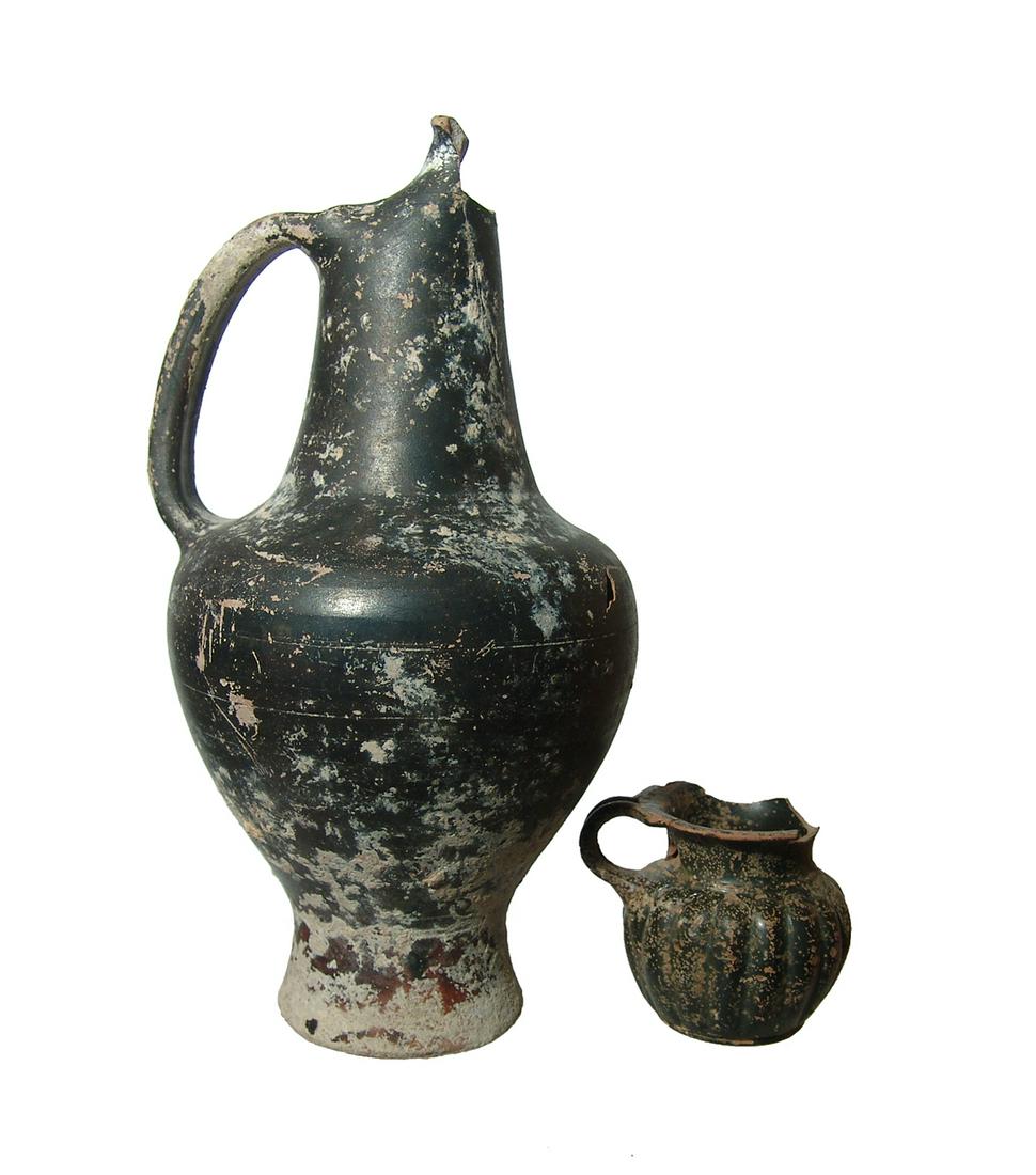 An Etruscan and Greek fragmented pair of vessels: An Etruscan and Greek fragmented pair of vessels. The first is an Etruscan oinochoe, c. 4th Century BC, for pouring wine, H: 8 3/8 in (21.3 cm), the second is a Greek black glazed ribbed olpe, 4th Cen
