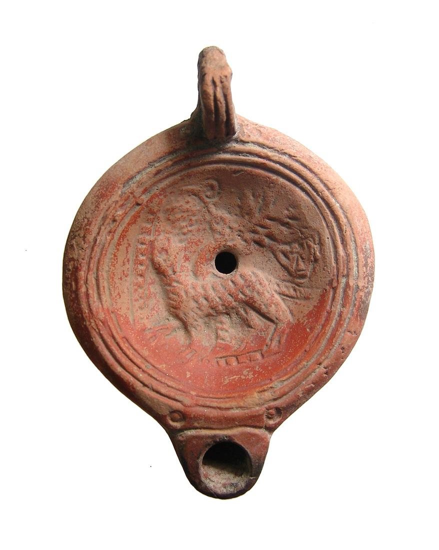 Roman ceramic discus lamp depicting panther: A Roman ceramic discus lamp depicting panther, 1st Century AD, with head upturned, grape vine hanging overhead and a full vase or basket behind. The discus is set off by a border of ridges and impress