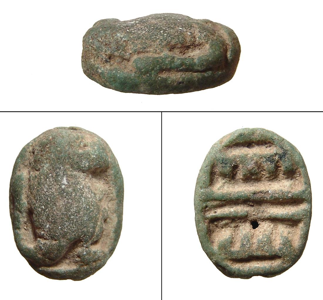 An Egyptian green faience scaraboid in baboon form: An Egyptian green faience scaraboid in the form of a baboon, Late Period, c. 664 - 332 BC, men signs on base. 21 x 16 mm. Cf. Matouk V. II, no. 826 for type; Ex Royal Athena Galleries, New York.