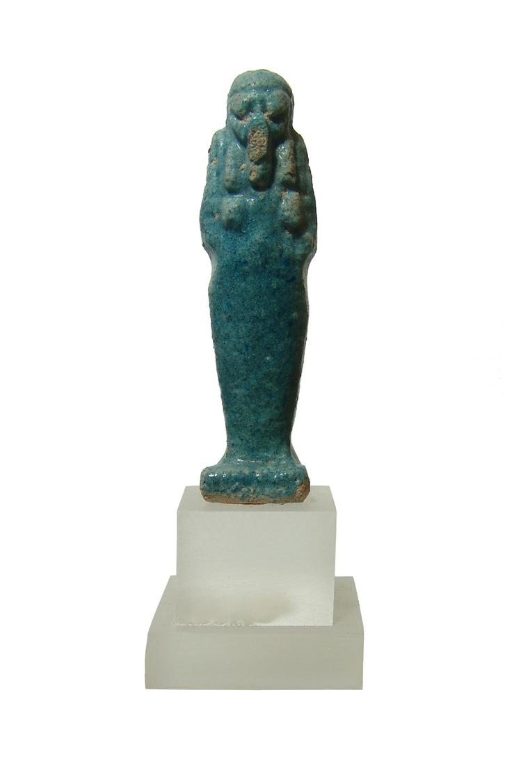 An Egyptian faience blue glazed ushabti: An Egyptian faience blue glazed ushabti, Late Period, c. 664-30 BC, mummiform, wearing tripartite wig and false beard, and arms folded across chest holding a pick and hoe in its hands, H: 3 1/8 in (8.