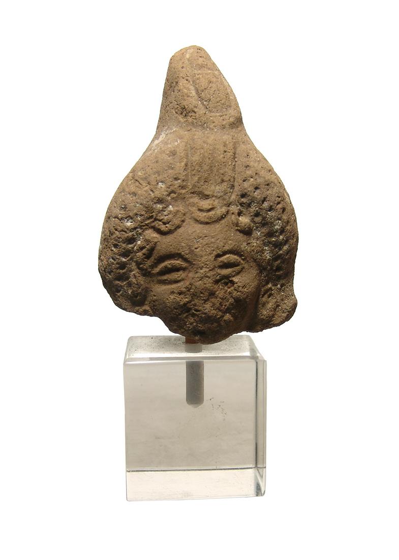 An Egyptian terracotta head of Harpokrates: An Egyptian terracotta head of Harpokrates, Ptolemaic, 3rd - 1st Century BC, with large, rolled wreath surmounted by double crown of Upper and Lower Egypt. H: 2 1/2 in (6.3 cm). Light deposits and mou