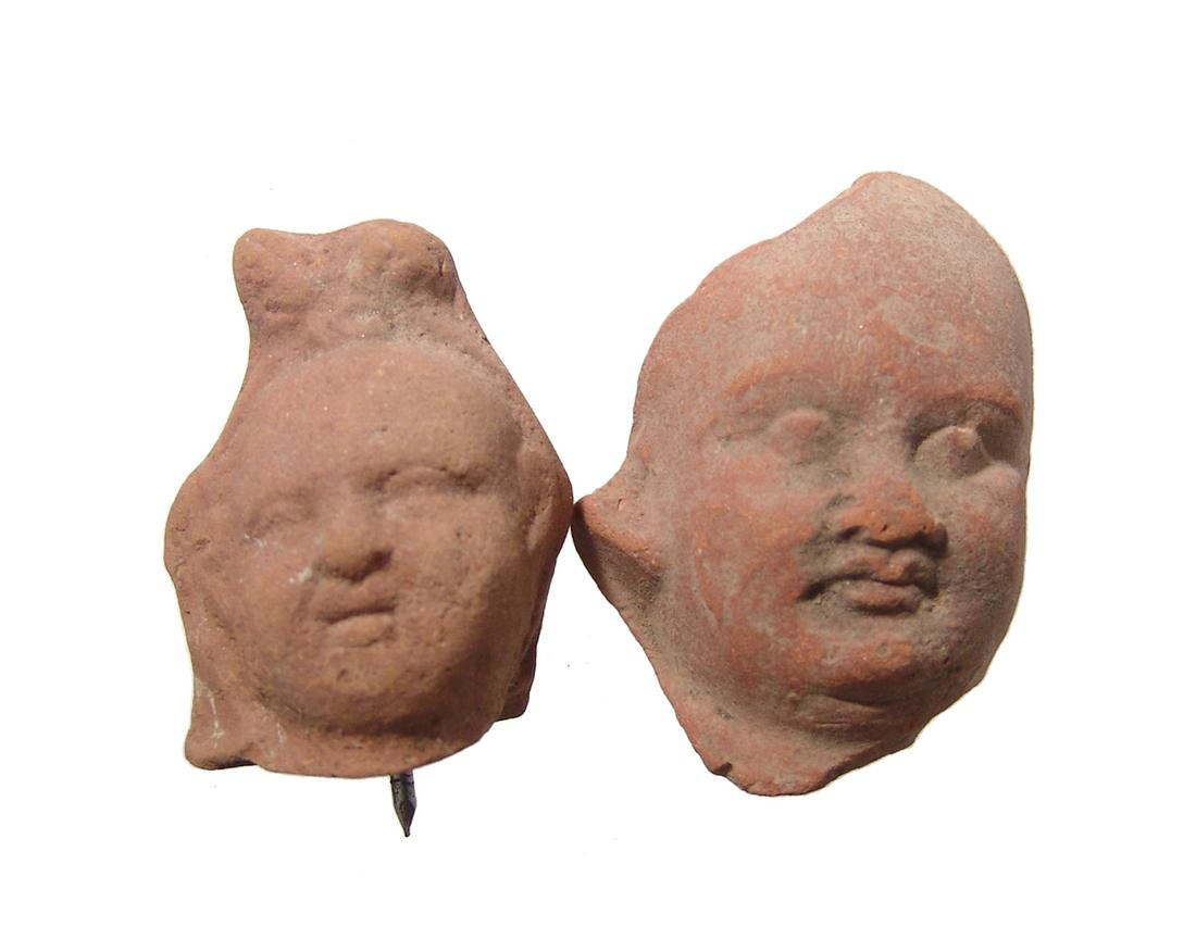 Pair of Romano-Egyptian terracotta Harpokrates heads: A pair of Romano-Egyptian terracotta heads depicting Harpokrates, c. 1st - 2nd Century AD, each with rounded features and good detail. H: 2 1/4 in (5.7 cm) & 1 3/4 in (4.4 cm). Light deposits. Ex Harv