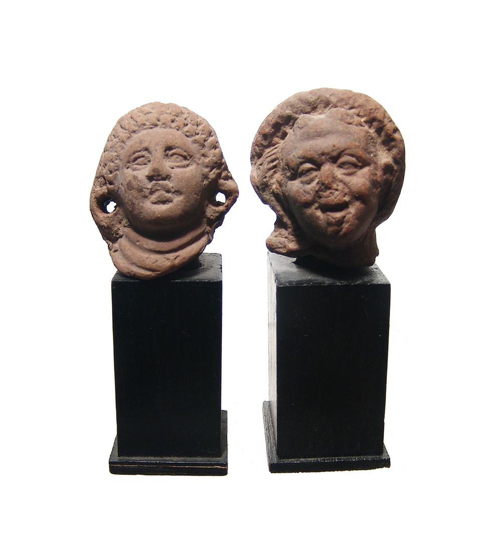 A pair of Romano-Egyptian terracotta heads: A pair of Romano-Egyptian terracotta heads. The first depicts the aged Harpokrates, 2nd - 3rd Century AD, wearing rolled diadem and side-lock, his features rather grotesque per the style. Deposits thr