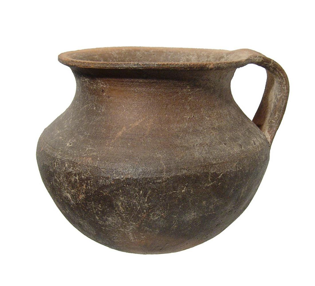 A Hellenistic round bottomed olpe: A Hellenistic round bottomed olpe, c. 4th - 2nd Century BC, orange buff with black mottling, the neck is short with flared mouth and a single strap handle. 4 x 3 1/4 in (10.1 x 8.9 cm). Well-preserved