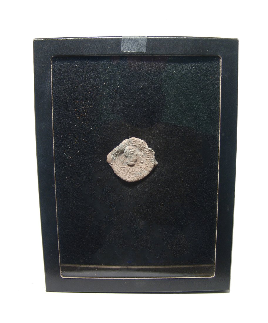 An Eastern European lead bottle stopper, dated 1603: An Eastern European lead bottle stopper, dated 1603, featuring a male head facing right. Above a line, V - U to sides and date 1603 below. Around the outside in an inscription. 1 5/8 x 1 3/8 in. (4.1 