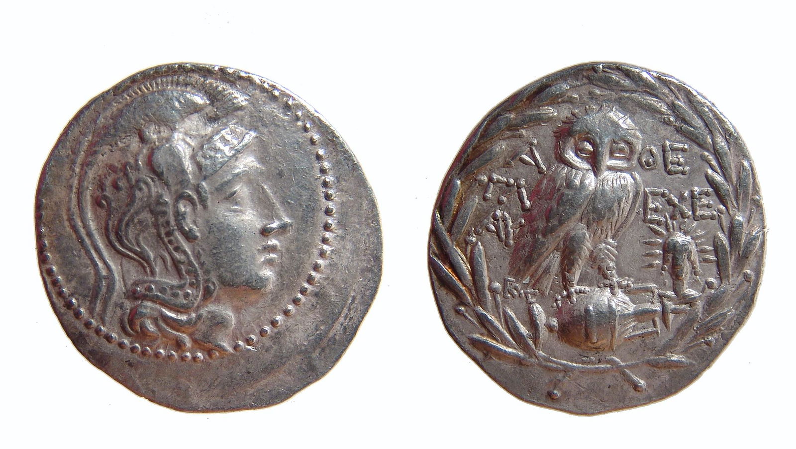 A silver New Style tetradrachm with owl of Athena: A silver New Style tetradrachm struck 138 - 137 BC at Athens, Greece. The obverse features the helmeted Athena and the opposing side an owl on amphora over head of Helios; all within an olive wreath.
