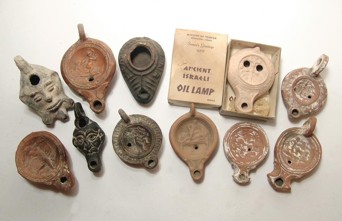 A group of 11 ancient-style replica oil lamps: A group of 11 ancient-style replica oil lamps. Lot includes examples with erotic scenes, a pair featuring Eros, a male dancer, two with the body in the form of male heads, and a Byzantine type with Gr