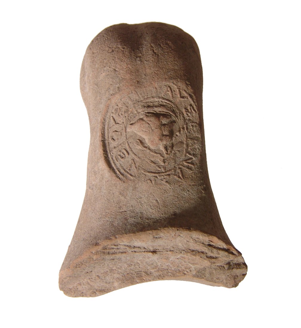 A stamped Rhodian handle from an amphora: A stamped Rhodian handle from an amphora, c. 4th Century BC, the stamp in the form of Greek inscription in relief circling a rose. 3 7/8 x 2 ½ in. (9.8 x 6.4 cm). Light deposits. Ex Tarshish An