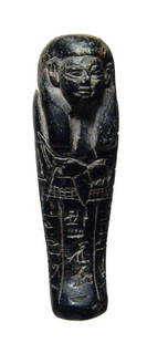 Nice black serpentine Ushabti, 19th Dynasty: A nice black serpentine Ushabti, Dynasty 19, c. 1293 – 1240 BC. Mummiform, wearing tripartite wig and holding pick, hoe and seed bags. H: 2 7/8" (7.3 cm). Ex New Hampshire collection.