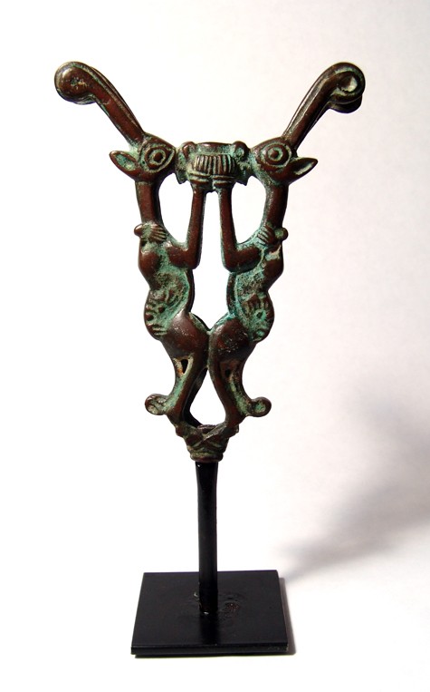Luristan bronze finial, two rampant goats: A Luristan bronze finial in the form of two rampant goats, Western Iran, c.1200 – 1000 BC, each clutching the side of a cup. Nice style and light green patination over glossy brown. H: 5" (12.5 cm).