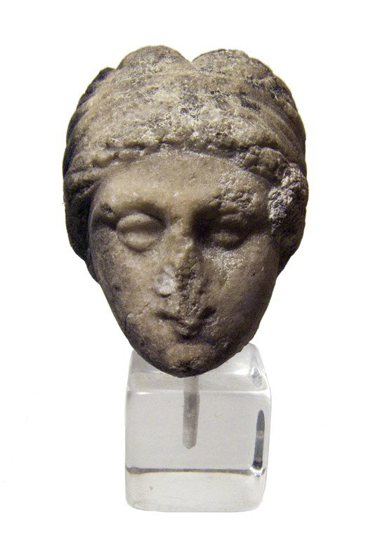 Nice Roman marble head of a female: A nice Roman marble head of a female, c. 1st - 2nd Century AD, perhaps Aphrodite. Her hair is wrapped in a scarf and pulled back into a chignon. Some blackening sue to an ancient fire, otherwise a nic