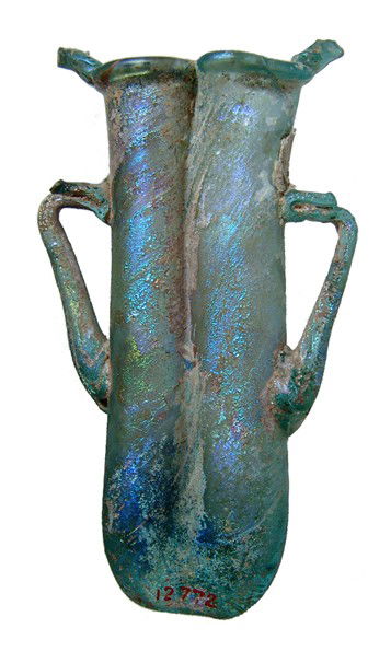 A light blue Roman glass double Balsamarium: A light blue glass double Balsamarium, 4th Century BC, the iridescence extremely beautiful. Two tubular vials are fused together, a handle to either side. Some losses to the trailing above the handles