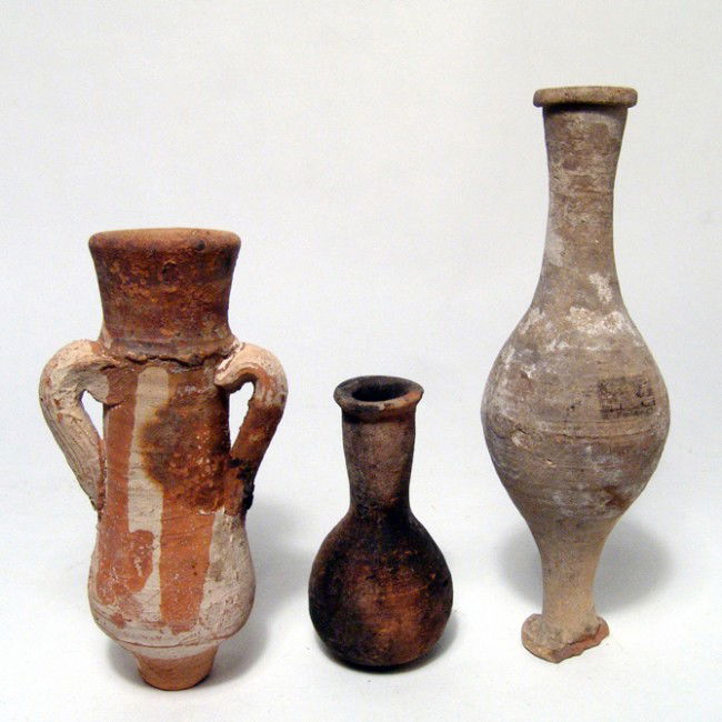 A lot of 3 Roman terracotta vessels: A lot of 3 Roman terracotta vessels, c. 1st - 4th Century AD, including a small red buff amphora with applied white and orange slip, L: 4 3/8" (11.1 cm), a spindle unguentarium, L: 5 5/8" (14.3 cm), a