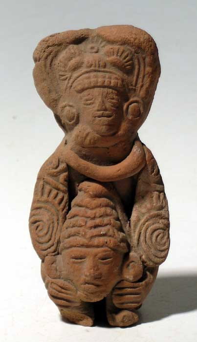 Elaborate Teotihuacan figure from Mexico: An elaborately molded Teotihuacan figure from Mexico, c. AD 400 - 650. It is 4" high and depicts an ornately attired priest holding the decapitated head of a sacrificial victim, whose importance is sh