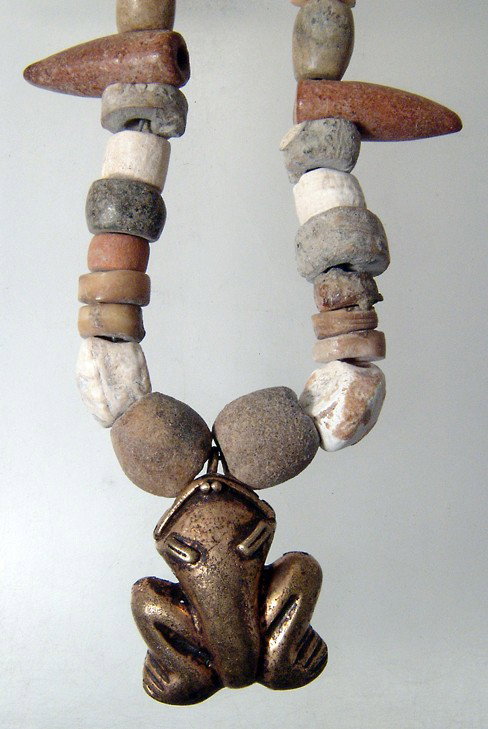 Tairona shell necklace with tumbaga, Colombia: A nice Tairona shell necklace with a tumbaga, Colombia, ca. 1000 - 1500. The tumbaga with some gold content and a nice rose-colored tone, L: 1 1/8" (2.9 cm). The necklace composed of cut shell beads, 