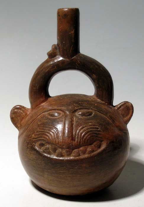 Choice Chimu zoomorphic vessel from Peru: A choice Chimu zoomorphic vessel from Peru, c. AD 1,100 - 1,450. It is 7" high and portrays a puma head. The feline is shown with a broad grin which reveals a mouth full of teeth. The streaky finish o