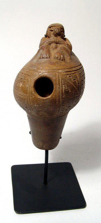 Tairona shell ocarina with seated human adorno: A nice Tairona shell ocarina with seated human adorno, Colombia, c. AD 1000-1500. An attractive example with incised decorative band and traces of red slip. H: 5" (13 cm). Intact and nicely mounted on