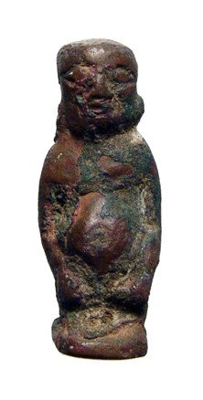 Egyptian bronze dwarf amulet, Late Period: An Egyptian bronze amulet in the form of a pot-bellied dwarf, Late Period, c. 664 - 30 BC. A rather odd amulet form with detailed facial features and characteristic plinth at back. Holed for suspensio