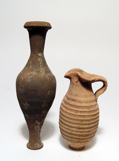 Pair of Roman terracotta vessels: A pair of Roman terracotta vessels. The first is a spindle bottle, c. 1st - 2nd Century AD, with black slip, L: 6" (15.2 cm); the second is a tan buff olpe with heavily ribbed body, L: 3 7/8" (9.9 cm)