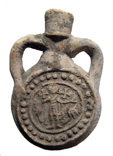 Terracotta souvenir pilgrim flask, Coptic Egypt: A terracotta souvenir pilgrim flask, Coptic Egypt, c. AD 480 - 650, depicting Saint Menas on one side, flanked by camels, his arms outstretched in blessing. Above each arm is a quincunx, representing 