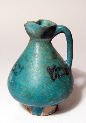 Attractive Nishapur turquoise glazed jug, Iran: An attractive Nishapur turquoise glazed pottery jug, North East Iran, c, 12th Century, with trefoil spout and single handle, the body with black pseudo-script. H: 4" (10.2 cm). Intact with deep color.